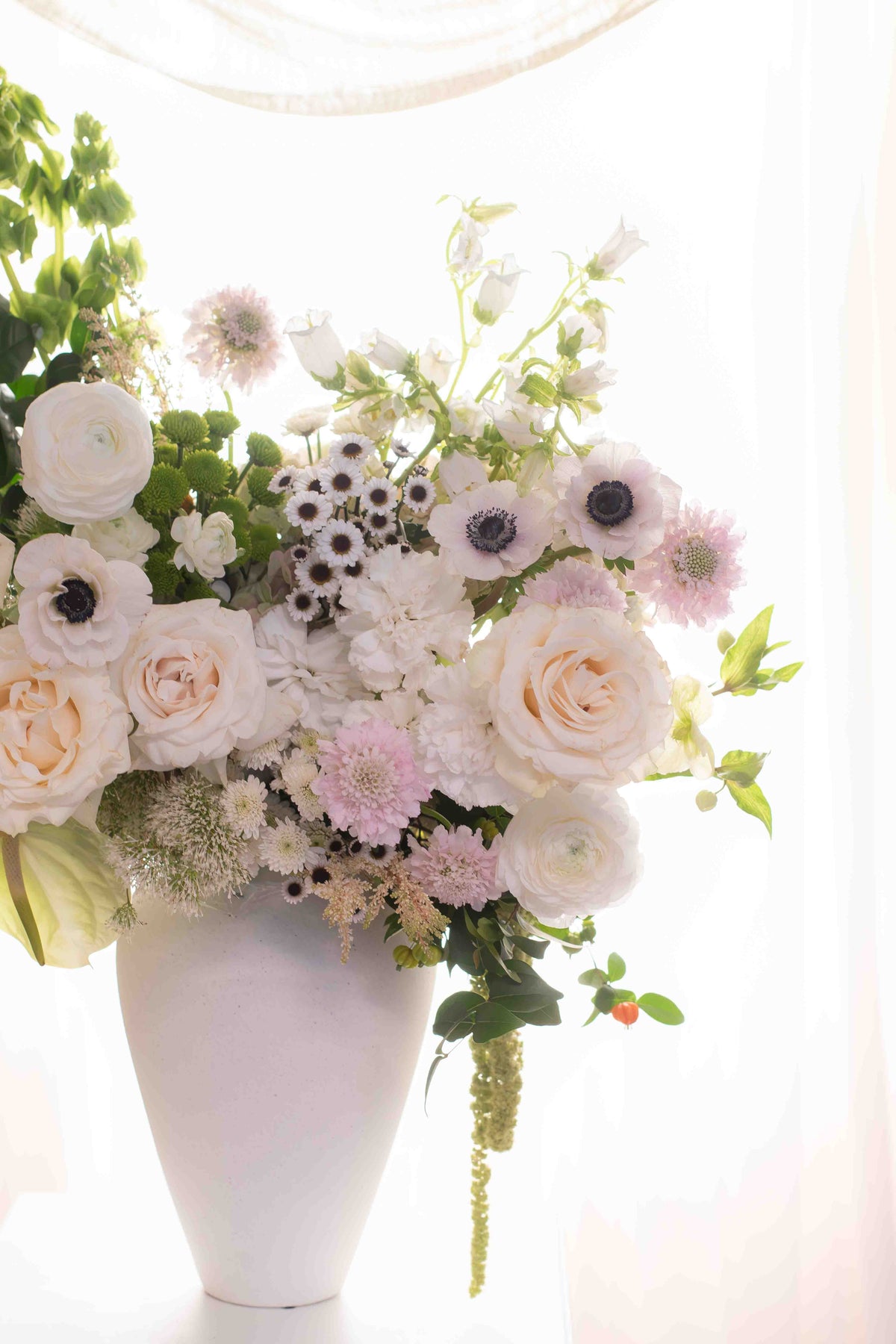 Aura Serena, arreglo floral en florero de cerámica blanca con rosas de lujo y anémonas, Clementina Medellín