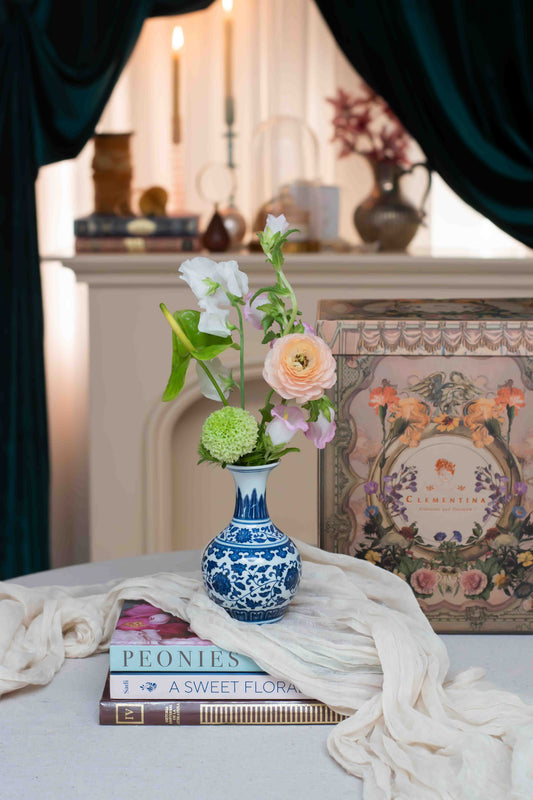 Florilegio, composición floral en cerámica holandesa azul y blanca sobre mesa con libros, Les Petits de Clementina Estudio Floral Medellín