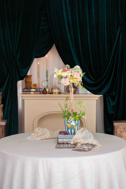 Petit Topiario sobre mesa con mantel blanco y cortinas verdes, Les Petits de Clementina Estudio Floral Medellín